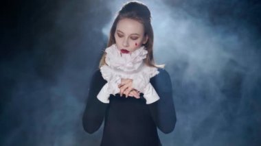 Actress standing at spotlight in darkness shaking tongue looking at camera imitating falling asleep. Portrait of talented Caucasian young woman playing madness in show posing