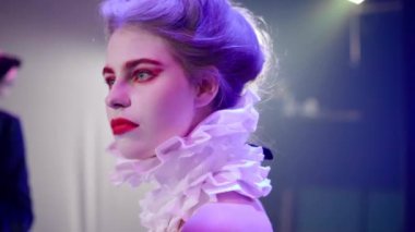Actress imitating fight with shocked facial expression getting hit and strike back. Portrait of young Caucasian woman with white face and red makeup playing on stage in theatrical performance