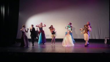 Wide shot theater stage with actresses dancing fast as actors moving slowly and joining funny rapid dance. Professional talented young Caucasian men and women acting performing modern show