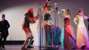 Actor and actress spinning cage with barefoot woman on stage curtsying. Caucasian skilled men and women performing contemporary art show in theater in vintage-style costumes