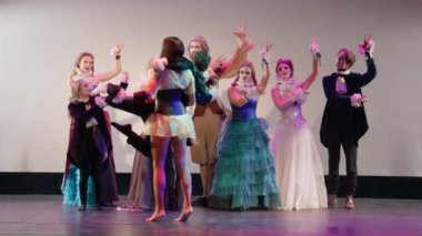 Portrait of talented actress spinning actor on stage with troupe clapping rejoicing standing at background. Caucasian young skilled men and women playing in theater show