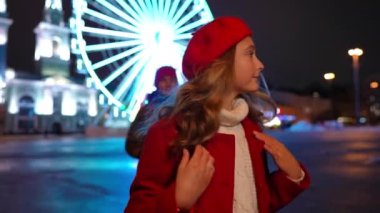 Beautiful teen girl looking around as boy surprising girlfriend with bouquet of flowers. Portrait of loving happy Caucasian teen couple dating in urban city at Valentines night. Slow motion