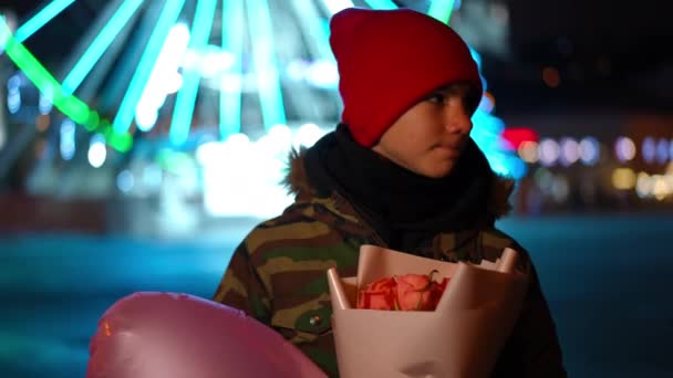 热切的白人少年男孩等待着与一束鲜花和气球的约会 一个英俊的少年站在夜市大街上环顾四周的画像 初恋与忧虑的概念 — 图库视频影像