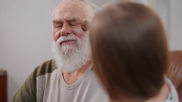 Bearded Old Man Closing Eyes Smiling Blurred Girl Applying Face — стоковое видео