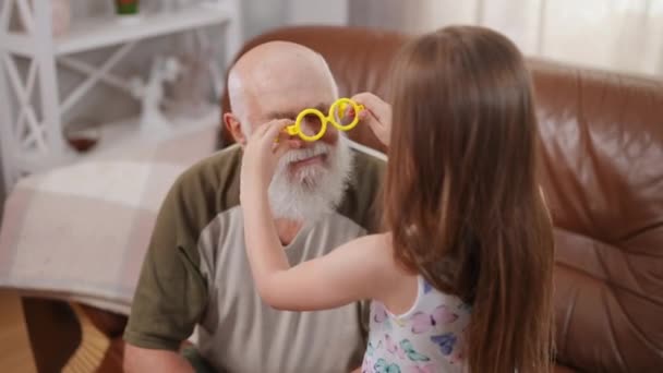 Bearded Senior Grey Haired Grandfather Sitting Couch Granddaughter Putting Yellow — 图库视频影像