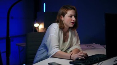 Young gorgeous slim woman laughing typing on PC keyboard looking at screen. Portrait of cheerful beautiful Caucasian freelancer enjoying messaging online in garage office