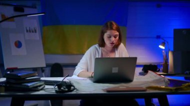 Front view portrait of confident positive beautiful young woman messaging online closing laptop looking at camera smiling. Charming slim Caucasian startuper posing in garage indoors