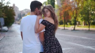 Live camera zoom in to confident beautiful young woman posing in slow motion hugging man standing on city street. Portrait of gorgeous slim girlfriend dating with boyfriend in urban town