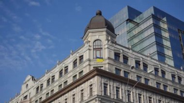 Ancient building with modern house at background of blue cloudless summer spring sky outdoors. Vintage architecture combined with contemporary in urban city in Kyiv Ukraine
