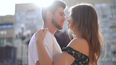 Live camera panning around loving hugging millennial happy couple standing on city street in sunshine. Confident positive Caucasian young handsome man and beautiful woman embracing in sunlight