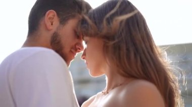 Close-up zoom in to tender loving young Caucasian couple face to face in sunrays outdoors. Happy confident millennial bearded handsome man and beautiful slim woman rubbing noses in slow motion