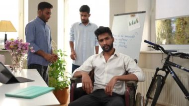 Tekerlekli sandalyedeki yakışıklı genç adam arkadaşlarıyla içeride poz verirken yüzlerine dokunmayı düşünüyor. Kazadan sonra bin yıllık erkek portresi ve arka planda düşünceli arkadaşlar.