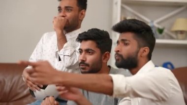 Heyecanlı genç Orta Doğulu erkekler TV 'de spor maçı izleyip cips yiyorlar ve konuşuyorlar. Hafta sonu hobi toplantısından keyif alan konsantre erkek arkadaşlarının yan bakış açısı portresi.