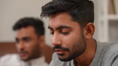 Yakın plan sakallı genç adam cips yiyor gülümsüyor bulanık arkadaşıyla konuşuyor oturma odasında televizyon seyrediyor. Yakışıklı Orta Doğulu adam hafta sonları ev arkadaşı ile eğleniyor.