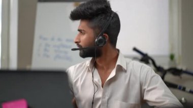 Kulaklıklı ciddi bir serbest çalışan. Masada dizüstü bilgisayarla oturuyor. İnternette sohbet eden Orta Doğulu yakışıklı bir adamın portresi.