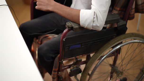无法辨认的年轻中东男子坐在轮椅上 在总部的网上为信息做手势 坐在室内耳机里自信的商务教练 — 图库视频影像