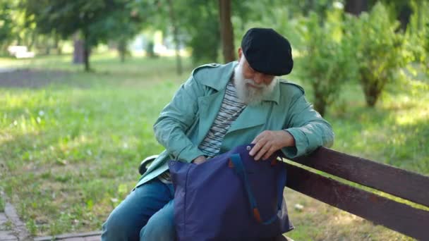 Уверены Старший Бородатый Мужчина Ищет Сумке Сидя Скамейке Городском Парке — стоковое видео