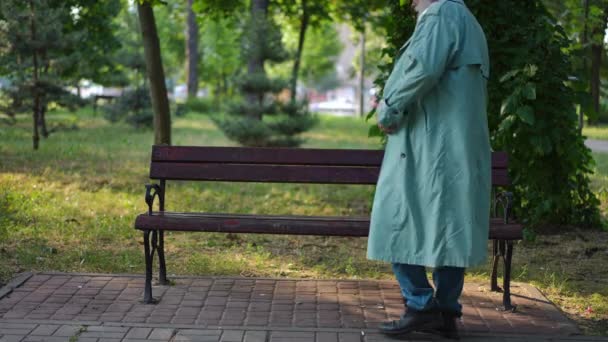 在城市公园的长椅上 坐着一个白种人 两手交叉地坐着环顾四周 有自信的男性退休人士在阳光明媚的夏日享受户外休闲 — 图库视频影像