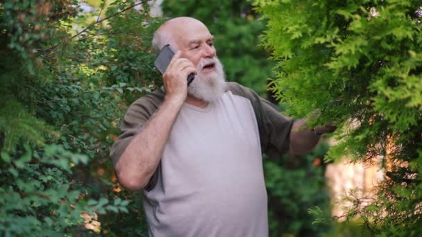 Tukang Kebun Laki Laki Senior Memotong Cabang Pohon Berbicara Telepon — Stok Video