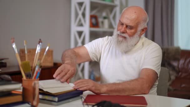 Senior Caucasian Man Turning Book Pages Reading Looking Camera Portrait — Stockvideo