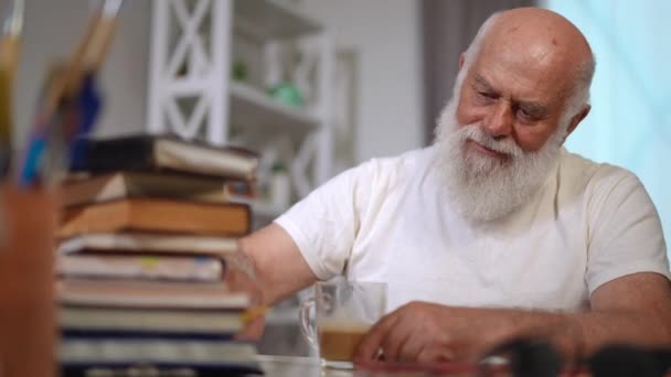 Senior Bearded Man Counting Books Table Shaking Head Sighing Leaning — Vídeo de Stock