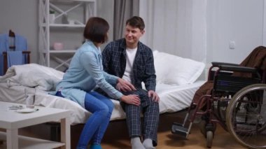 Kadın pijama giyip konuşmasına yardım ederken belden aşağısı felçli beyaz bir adam yatakta oturuyor. Mutlu koca ve sevgili karısı yatma vakti. Aile desteği ve bakım konsepti
