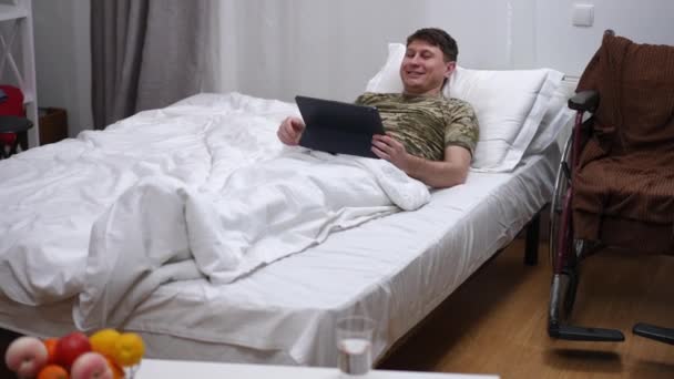Positive Man Military Shirt Lying Bed Messaging Digital Tablet App — 图库视频影像