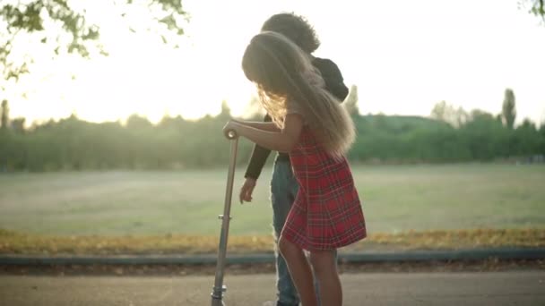 Seitenansicht Kamerafahrt Von Junge Hilft Mädchen Beim Kick Scooter Fahren — Stockvideo