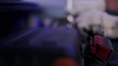 Arka planda İngiliz anahtarıyla oynayan bulanık erkek eli olan kapalı araba kaputu. Tanımlanamayan genç, beyaz mekanikçi kapalı alanda garajda otomobilin vidalarını sıkıyor.