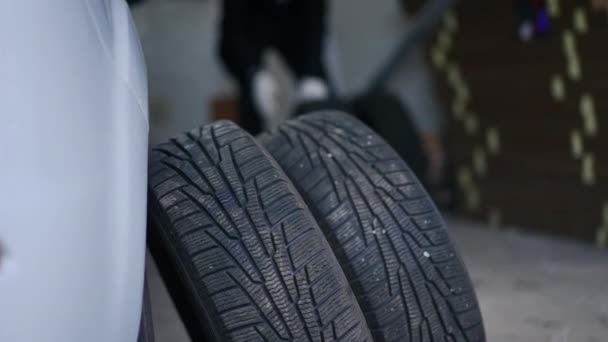 Zbliżenie Opon Samochodowych Pojeździe Garażu Zamazanym Człowiekiem Toczącym Się Bardziej — Wideo stockowe