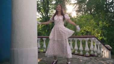 Klasik elbiseli, rahat, tatmin olmuş genç bir kadın gün ışığında dışarıda dönüyor. Kendine güvenen beyaz tenli kızıl saçlı güzel retro bayanın gün batımının keyfini çıkaran portresi.