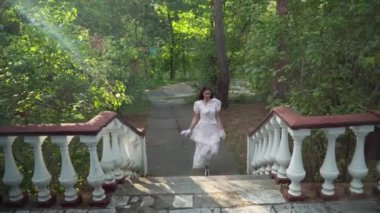 Wide shot joyful retro lady running upstairs from alley leaving. Happy young confident Caucasian woman in elegant retro dress outdoors on sunny spring summer day
