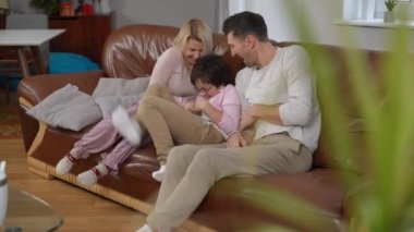 Kafkasyalı mutlu ebeveynler oğullarını gıdıklayarak eğleniyorlar. Neşeli bir kadın ve neşeli bir çocuk oturma odasında eğleniyor. Yaşam tarzı ve mutluluk