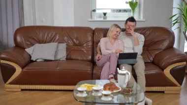 Rahat bir çift gülüyor, internette komedi filmi seyrediyor, çocuğun konuşmasını görmezden geliyor. Kafkasyalı anne ve babanın, oğlunun gidişini umursamayan geniş açılı portresi. Aile içi ilişki