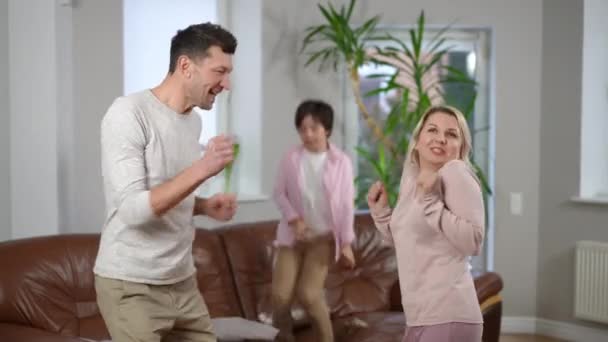 Radostný Pár Rodičů Tančících Obýváku Rozmazaným Veselým Synem Skákajícím Gauči — Stock video