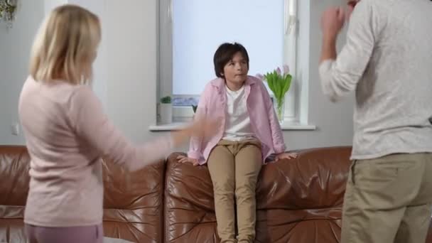 Disobedient Boy Sitting Couch Unrecognizable Parents Gesturing Scolding Kid Indoors — Stock Video