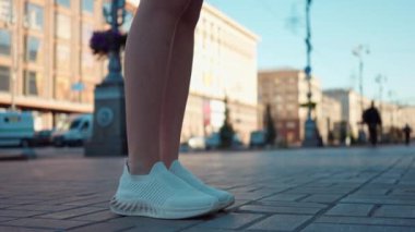 Asfaltta duran genç kadın bacakları sokakta yürümeye başlıyor. Şehir dışında gezen, tanınmayan beyaz bir gencin görüntüsü. Yaşam tarzı kavramı