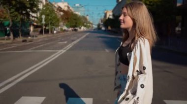 Kenar manzaralı, nakışlı tişörtlü, kenar mahalle caddesinden ağır çekimde gülümseyen güzel bir kızın portresi. Gün ışığında sağda yürüyen mutlu bir gencin görüntüsü.