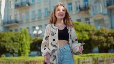Canlı kamera, şehir caddesinde poz veren yetenekli mutlu genç kıza zum yapıyor. Nakışlı Ukraynalı gömlekli kendinden emin bir gencin portresi kameraya bakarak sahneleniyor.