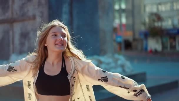 ライブカメラの回転ズームとして日当たりの良い街の通りで踊り手をストレッチ興奮した幸せな10代の女の子 明るい魅力的なティーンエイジャーの肖像画太陽の下でキエフウクライナで一日を楽しむ — ストック動画