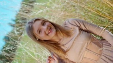 Sarı buğday tarlasında poz veren genç kız saçına çiçek takarken kamera dönüyor. Kendine güveni tam beyaz bir gencin, kameraya bakıp dışarıda eğlendiği portreyi büyüt.