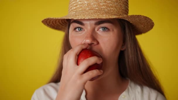 近距离前视年轻的黑发女人与灰色的眼睛吃维生素苹果看着相机 有自信的美丽白人女士慢动作享受美味有机水果的画像 — 图库视频影像