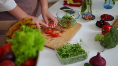 Masada salata için kırmızı domates kesen kadın eller. Tanımlanamayan beyaz bir kadın evde lezzetli sağlıklı yemekler pişiriyor.