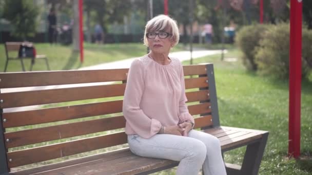 シニア女性の時計のベンチに屋外に座って時間を確認します 心配白人の退職者の路地を見て待っているの肖像画 直感とライフスタイルの概念 — ストック動画