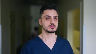 Ortadoğulu cerrahi üniformalı bir adamın portresi içeride dikilip duruyor. Klinik koridorundaki yakışıklı doktor. Yavaş çekim