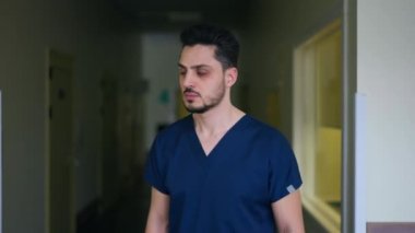 Kameraya bakan ciddi bir doktorun portresi yavaş çekimde uzaklaşıyor. Arkadan bakıldığında yakışıklı, yakışıklı, cerrahi üniformalı adam karanlık koridorda geziniyor.