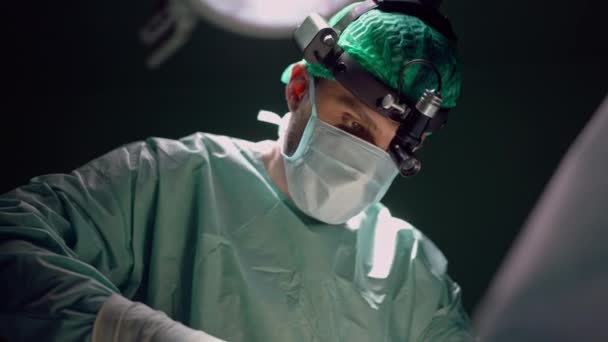 在室内进行慢动作手术的集中外科医生的底部角度视图 集中精神的中东男子在医院手术室做手术的画像 — 图库视频影像