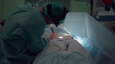 Uzman cerrah, göğüs implantı için tanınmayan bir kadının göğüslerindeki deliği genişletiyor. Orta boy Orta Doğulu doktor yavaş çekimde büyütme ameliyatı yapıyor.