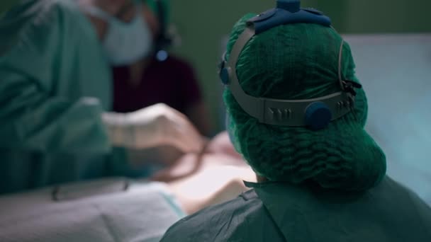 后视镜护士协助医生进行缓慢运动的隆胸手术 无法辨认的男女将植入物放置在手术室手术台上的病人胸围中 — 图库视频影像
