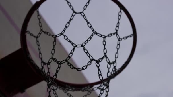 在灰蒙蒙的室外天空的背景下 特写篮球运动缓慢 带着金属网通过篮筐 街头角色扮演游戏得分 — 图库视频影像